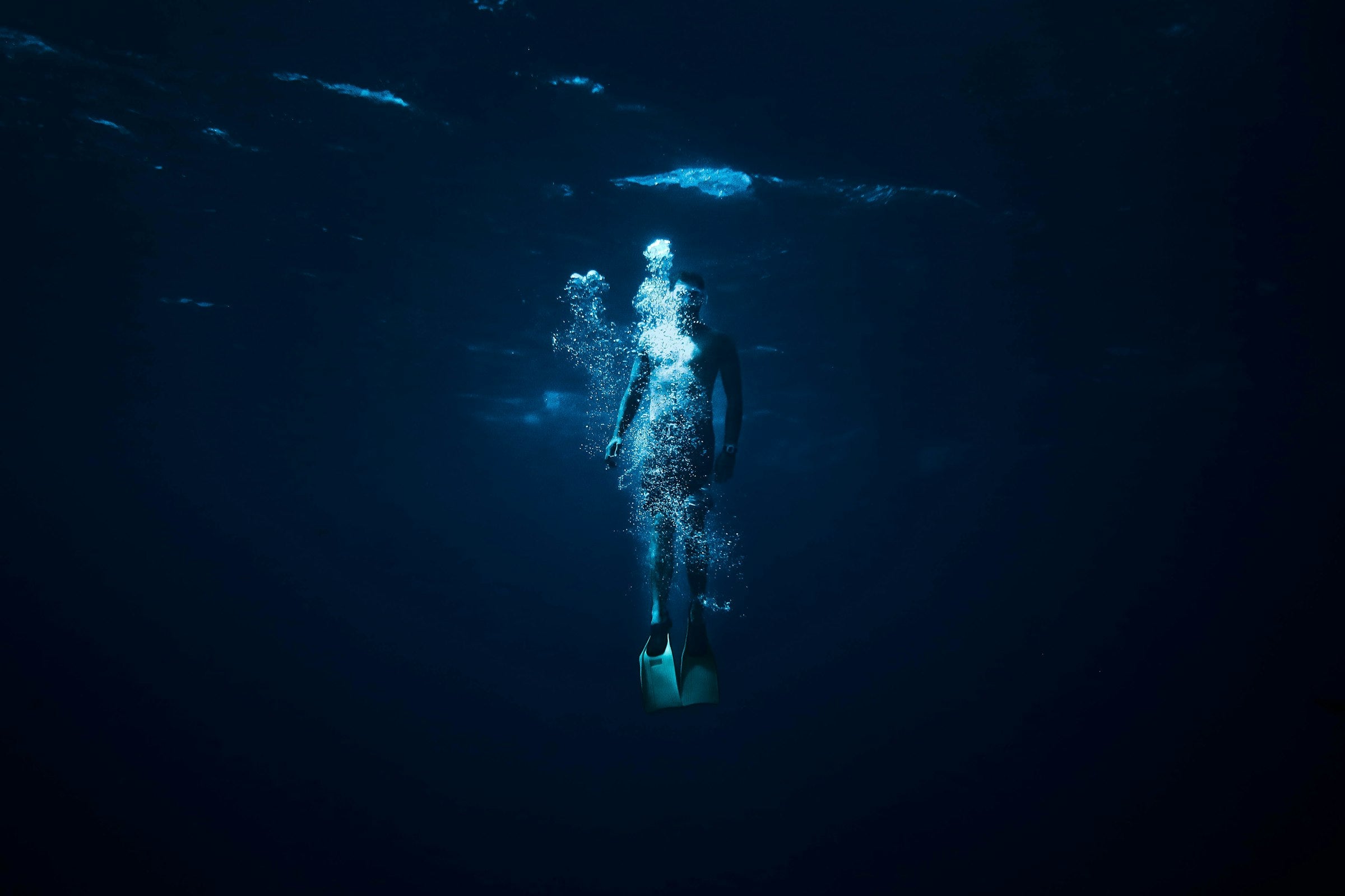 Freediver underwater surrounded by bubbles